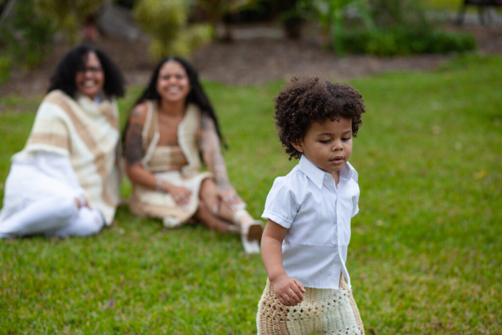 Young boy runs toward camera with his family in the background