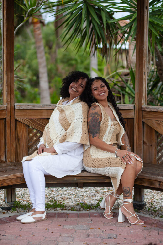 Mom and daughter seated back to back smiling for photo