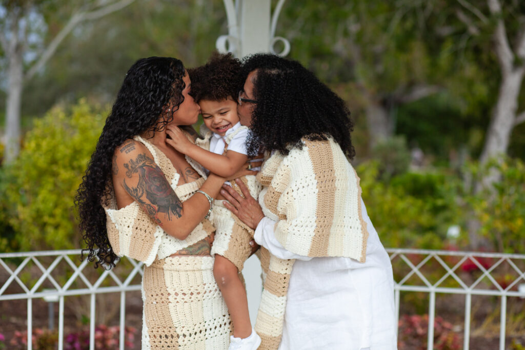 Young boy kissed on cheeks by his mom and grandma