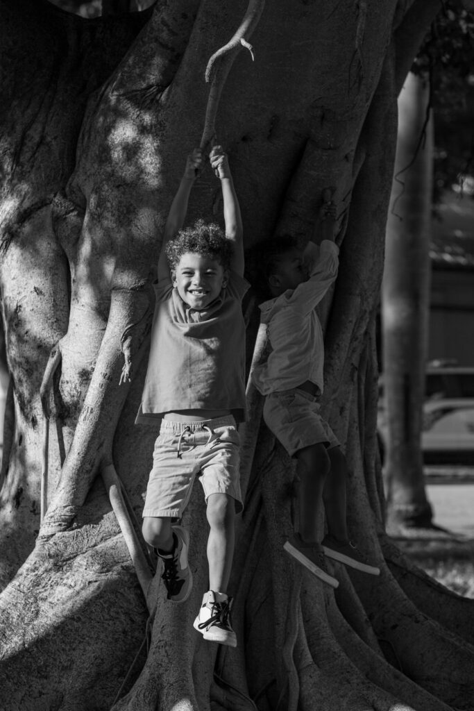 Black and white photo of two boys playing in a tree