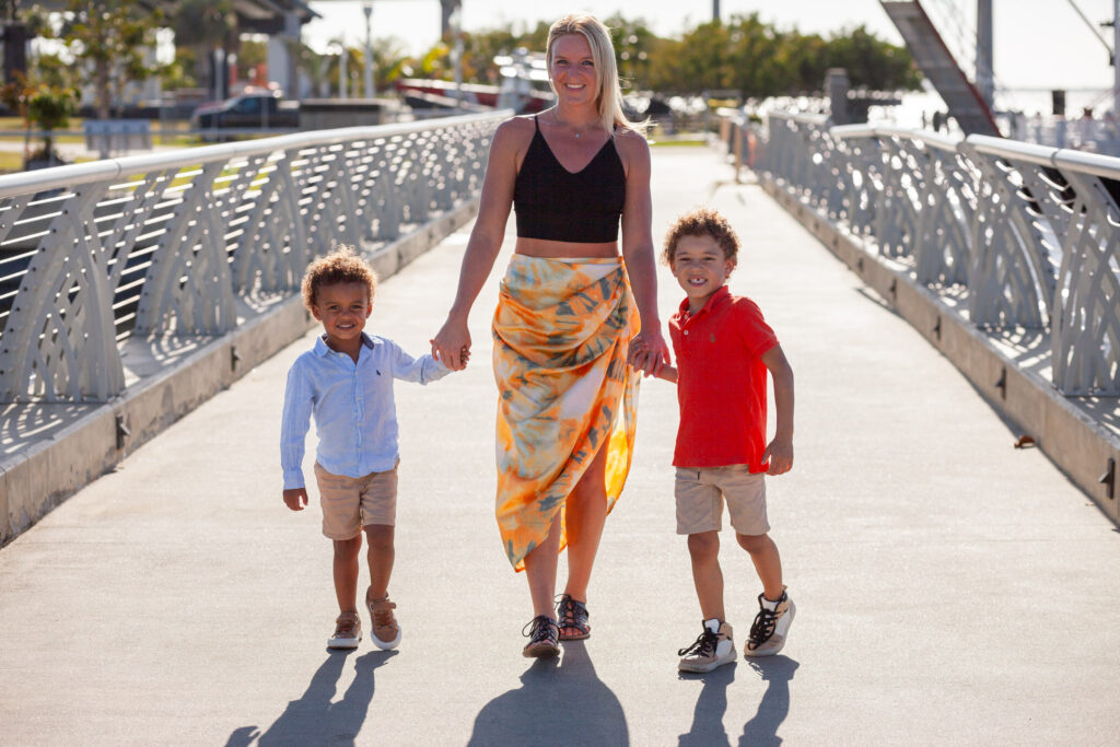 Mom holds two sons hands and walks towards camera