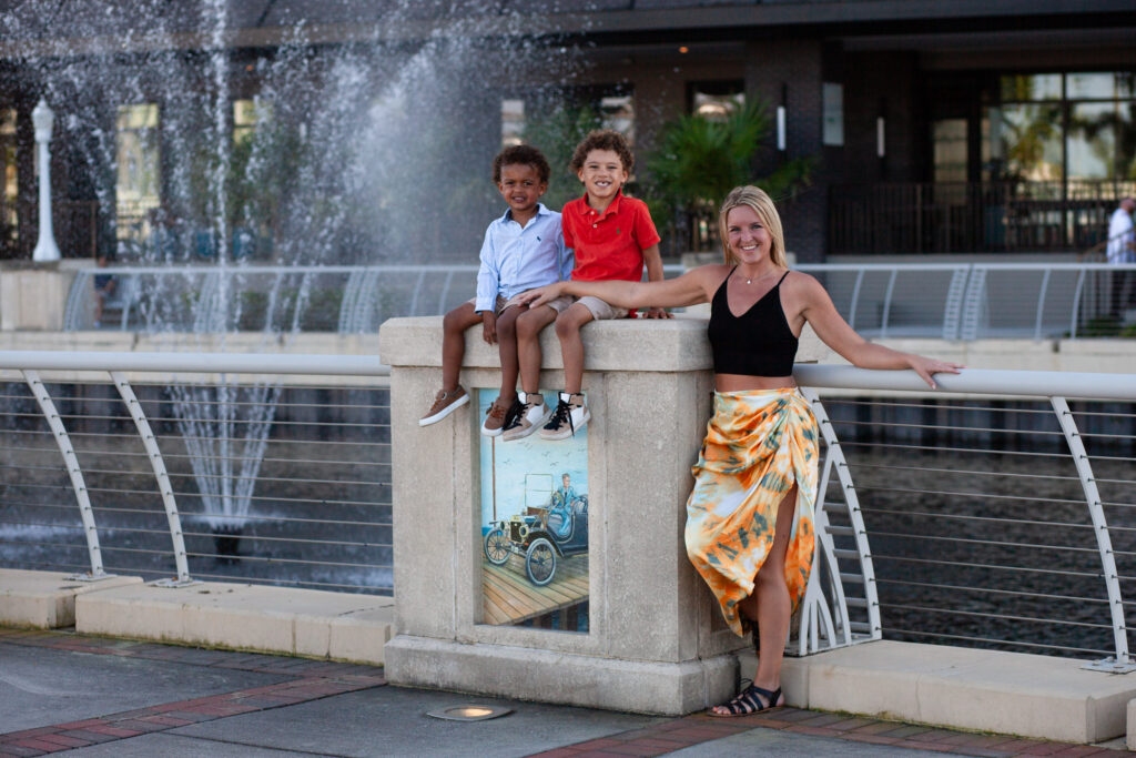 Two boys sit on a wall next to their mom