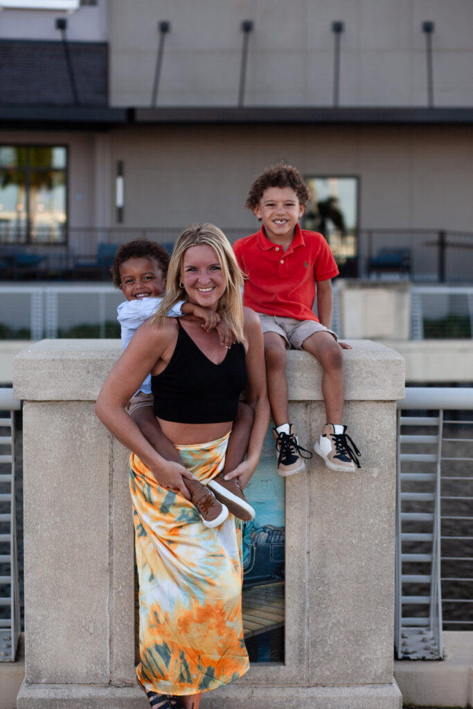 Mom gives piggy back to one son and second son is sitting behind them