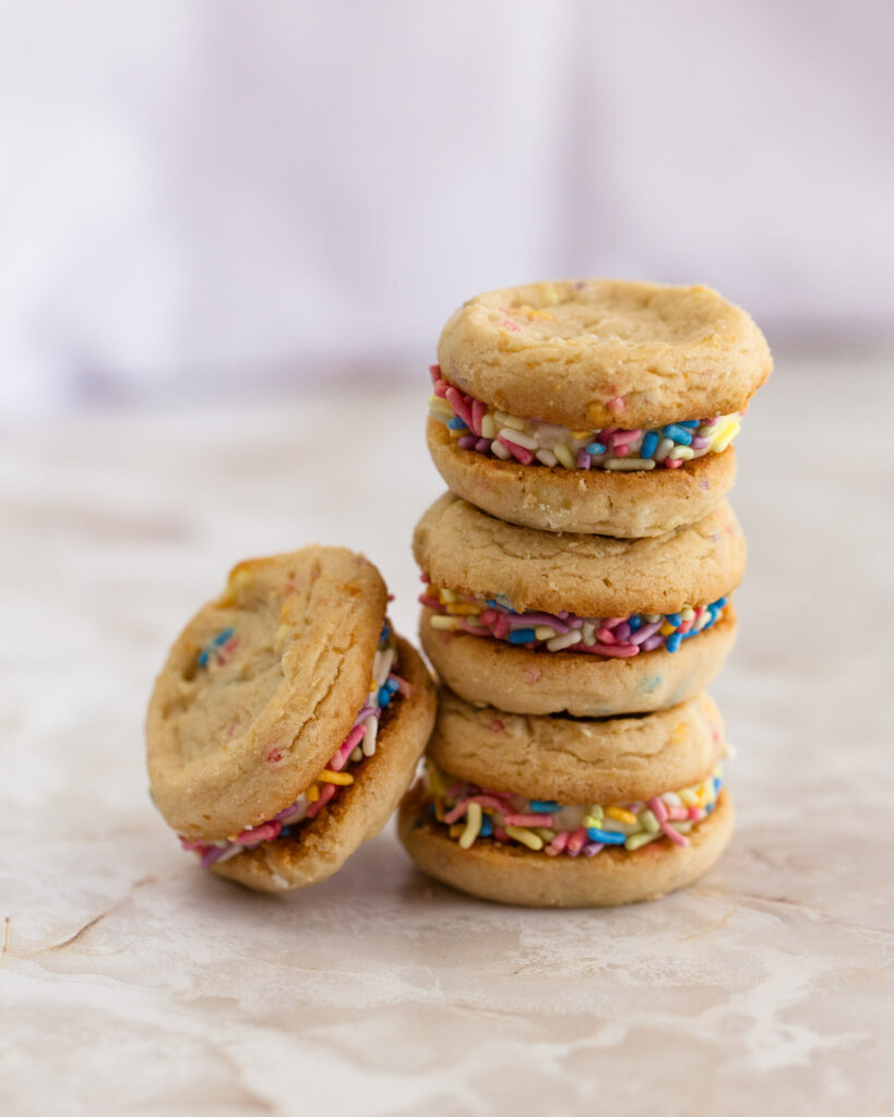 A stack of three funfetti sandwich cookies with another cookie leaning against them