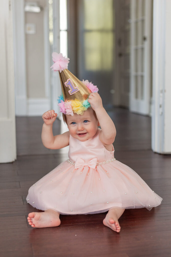 baby girl in pink dress and first birthday hat