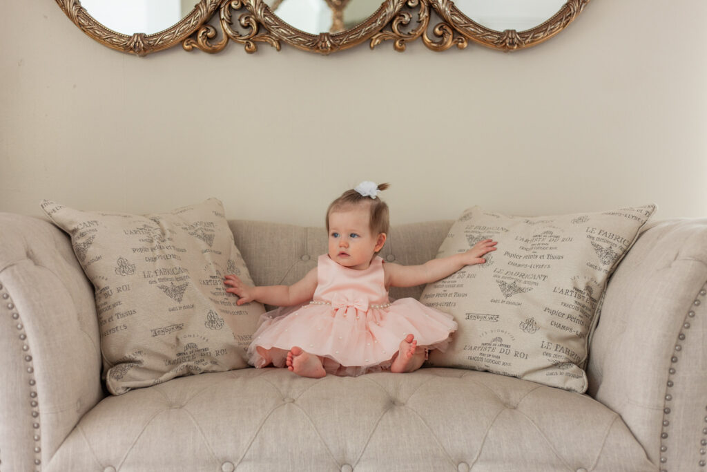 baby girl in pink dress on couch