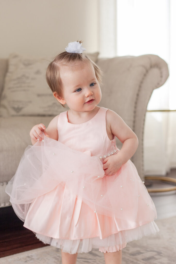 One year old plays with her pink dress