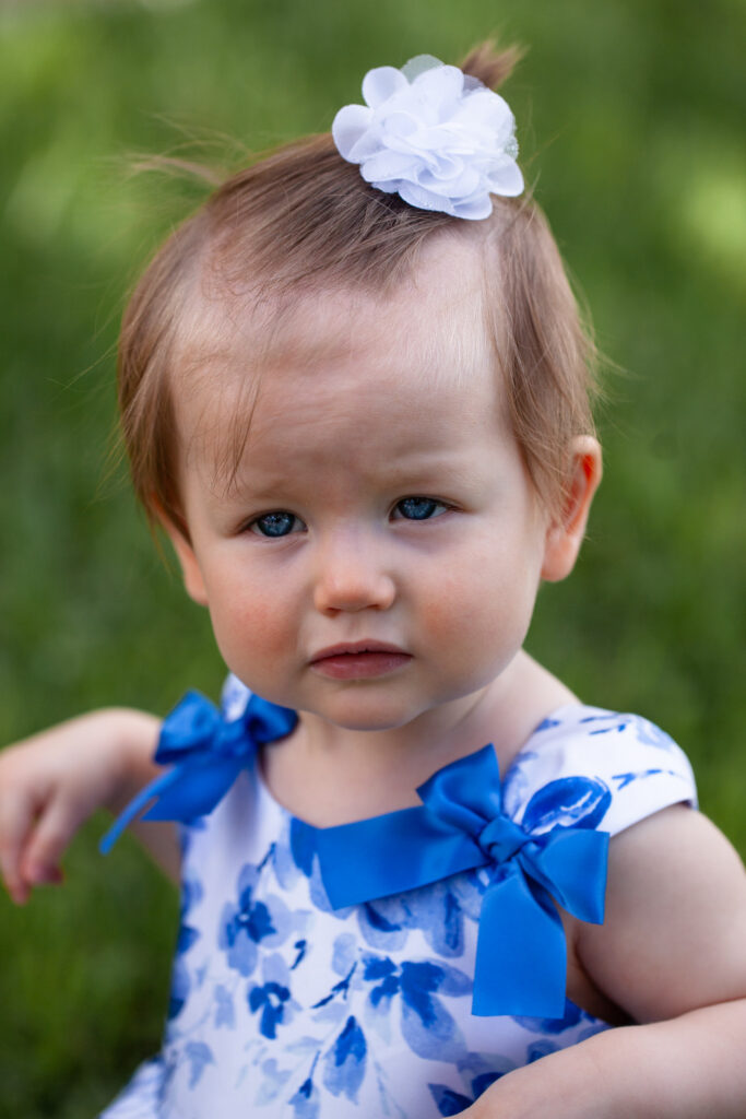 close up of blue eyed baby in blue dress