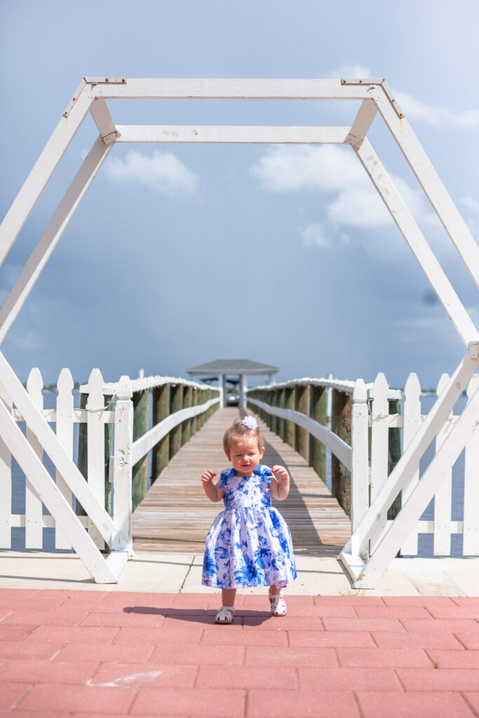 baby girl stands under arch for a photo