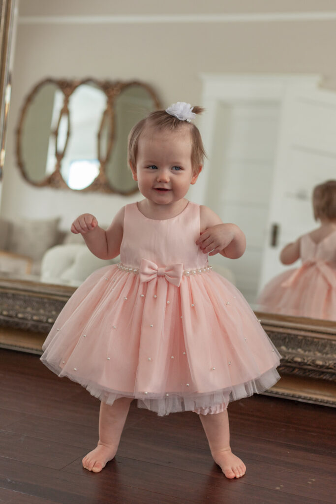 baby girl standing in pink dress