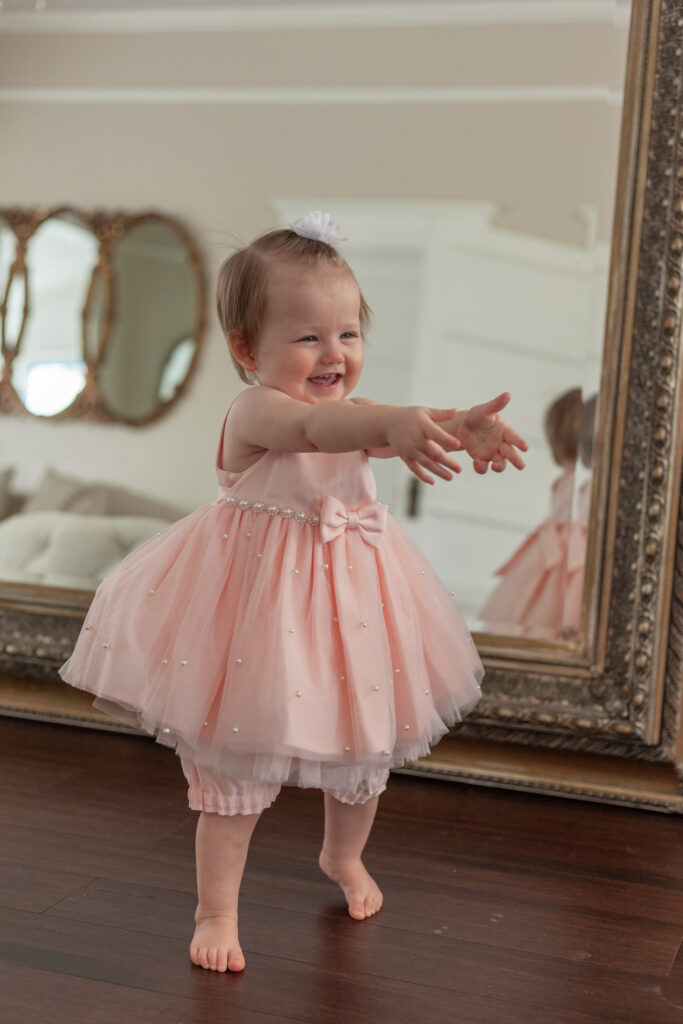 one year old walking with arms outstretched