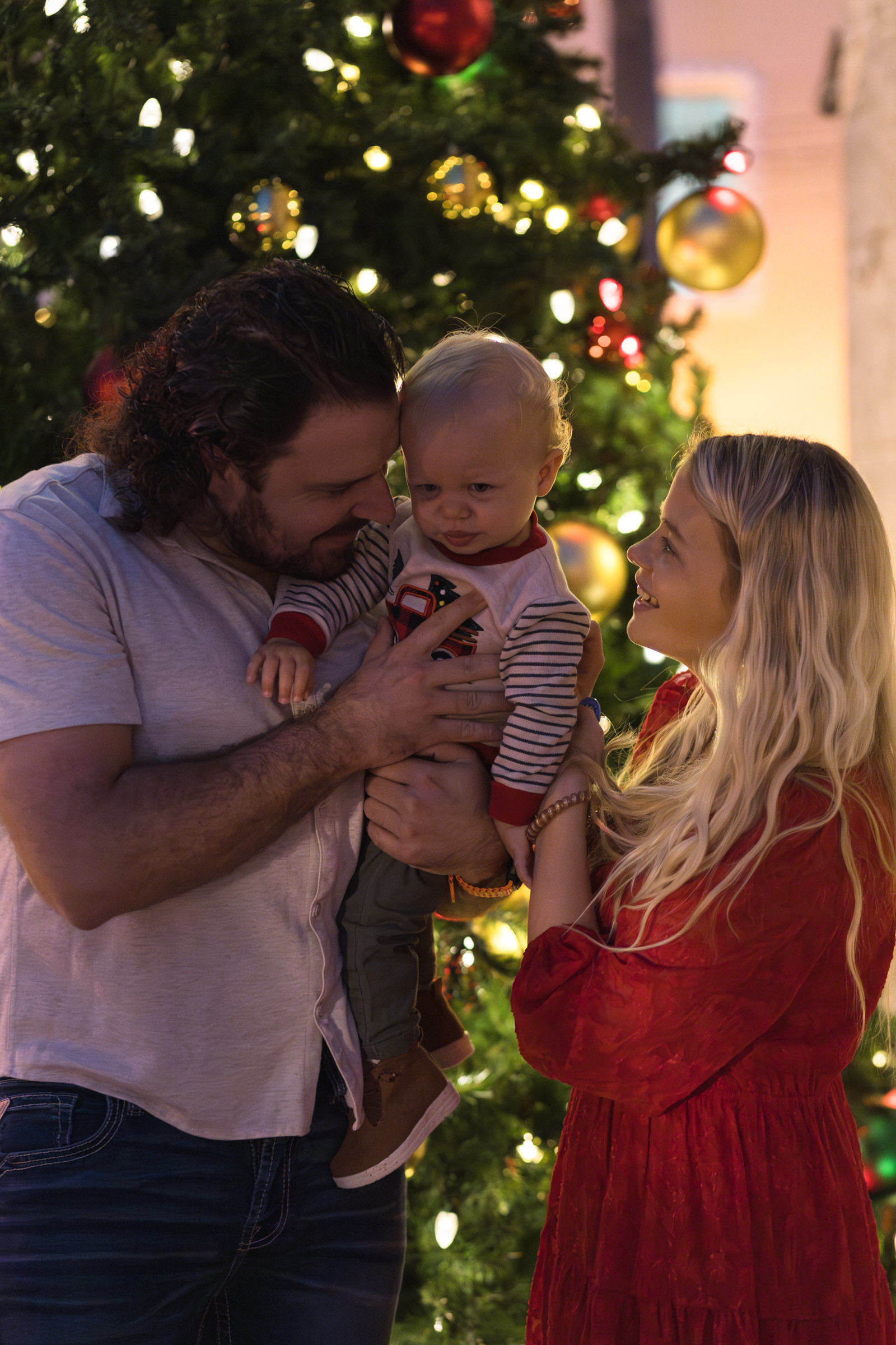 Family cheers up young boy in front of large Christmas tree
