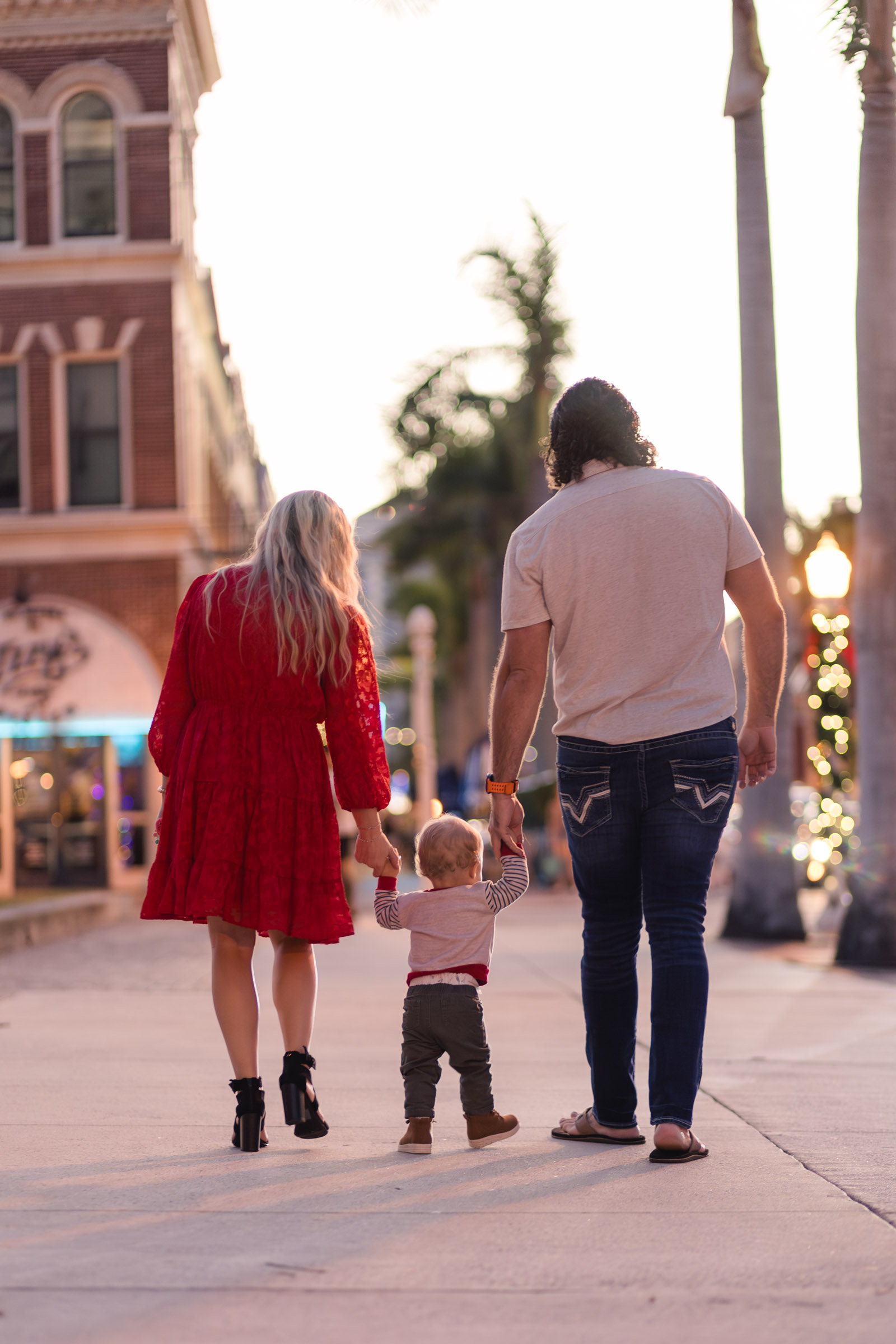 Family of 3 walks away holding hands on Downtown Fort Myers sidewalk