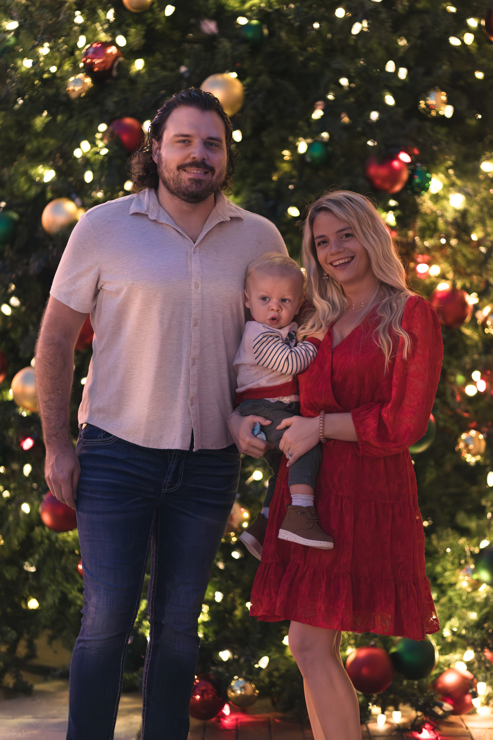 Family of 3 poses in front of the Sidney & Berne Davis Art Center Christmas tree in Fort Myers