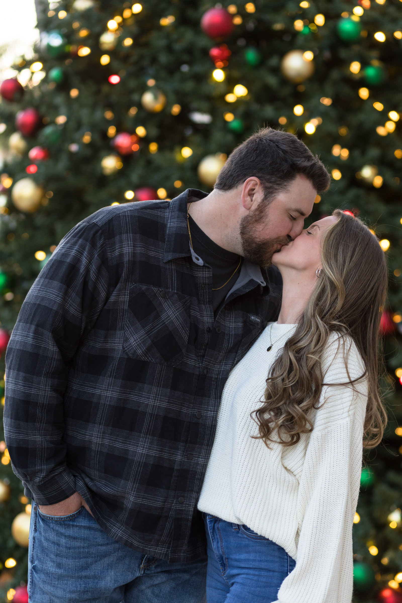 Couple kisses in front of Fort Myers Christmas tree background