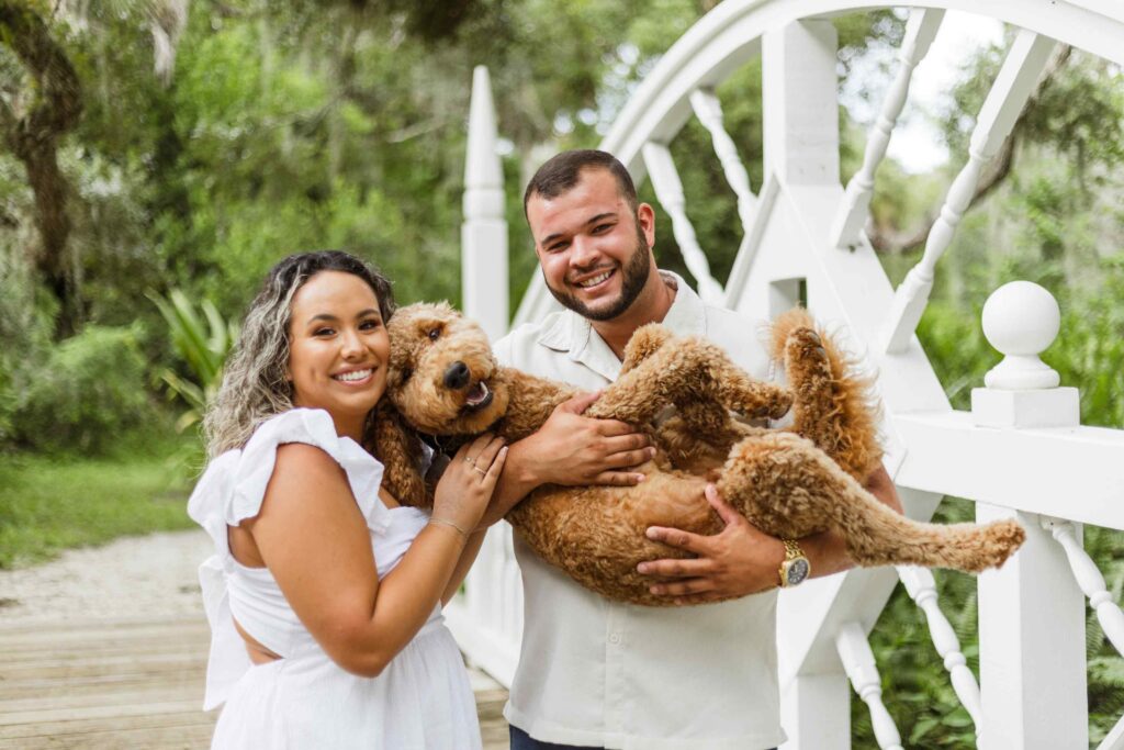 Couple holding their goldendoodle for a photo at Koreshan State Park