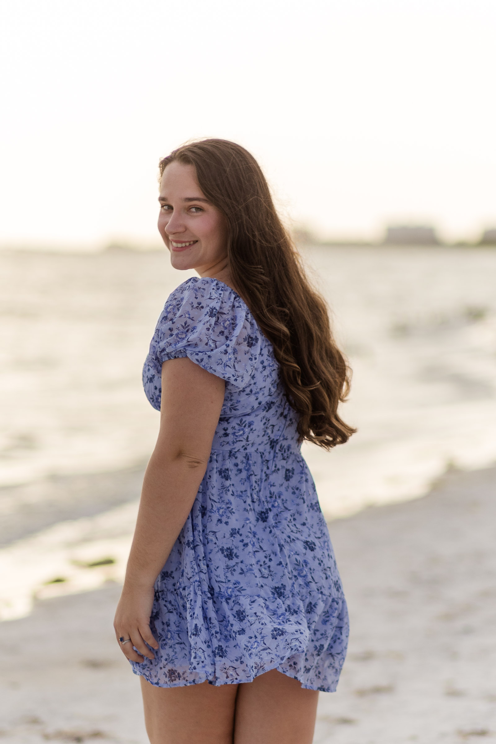 Woman in blue dress walking away and smiling back at the camera