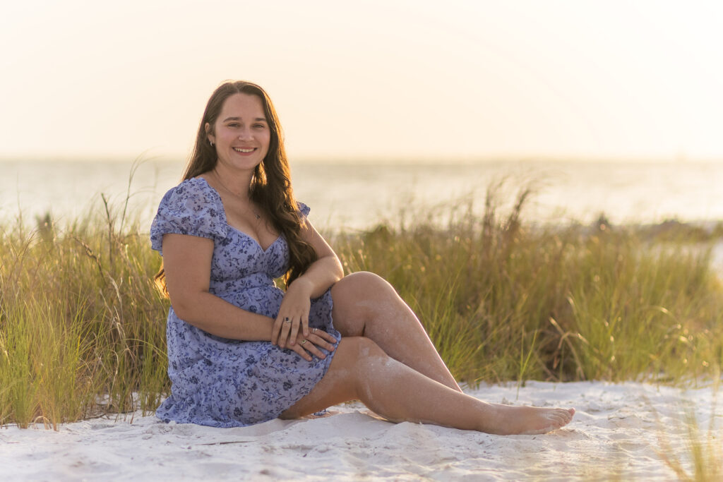 Woman sitting in blue dress in beach grass