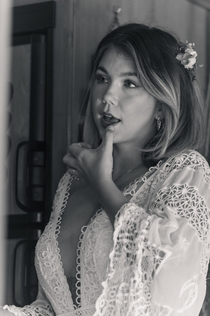 Black and white image of bride fixing her lipstick with her thumb