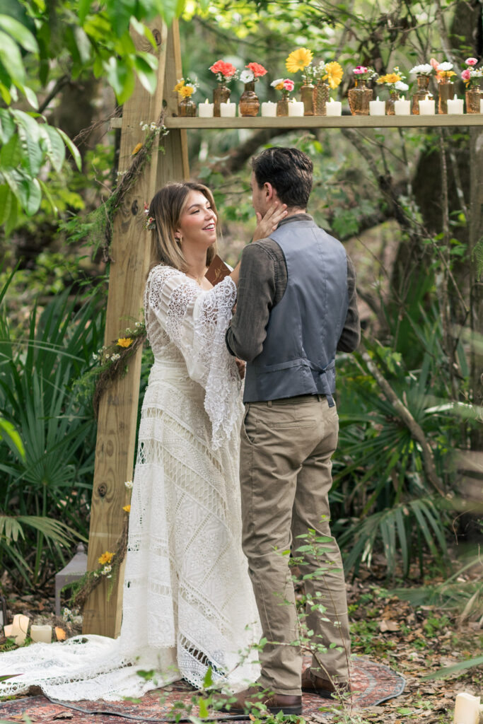 Bride touches her grooms cheek as he says his vows at the altar