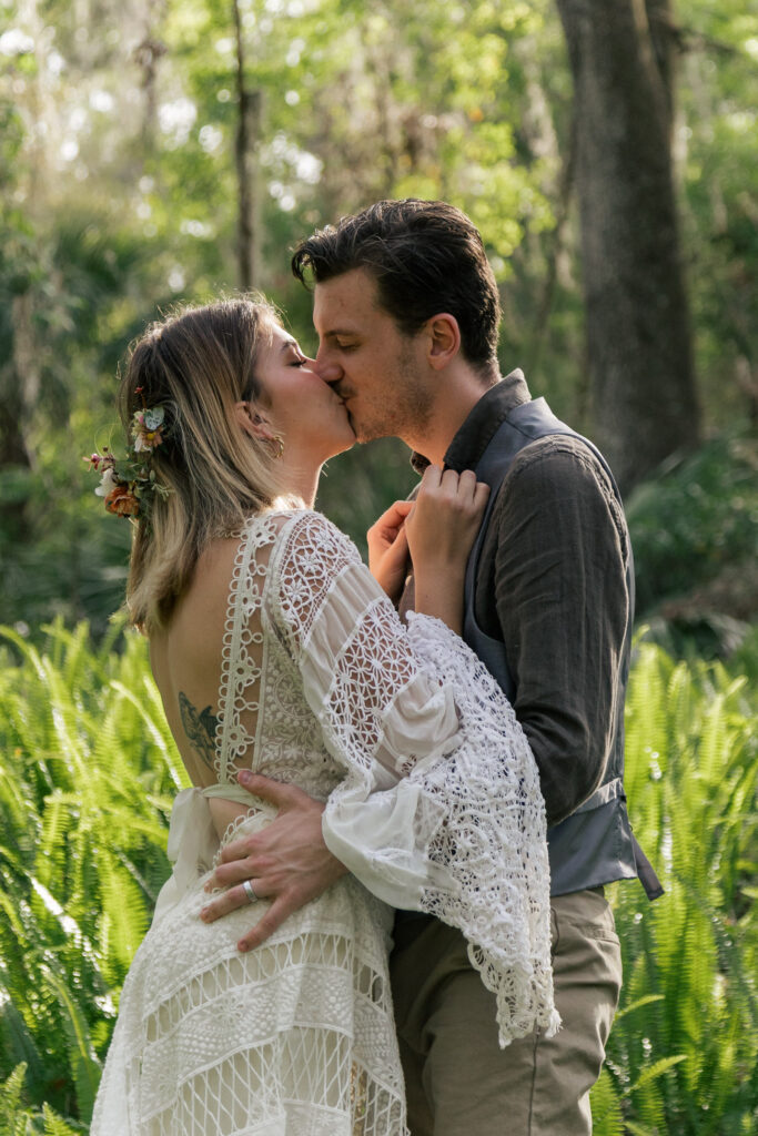 Couple kissing in a field of sunlit ferns