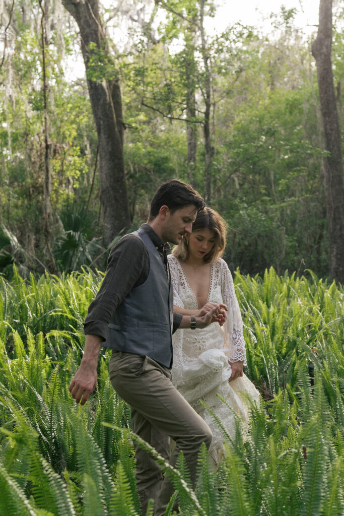 Groom leads his bride out of a field of ferns
