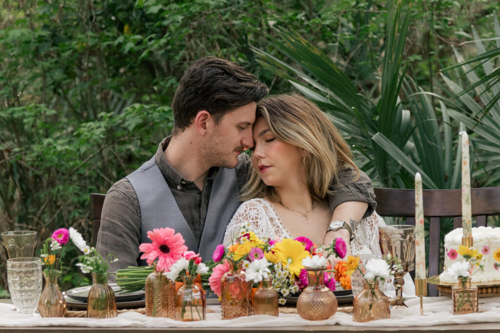 Couple leans their foreheads into each other at their elopement table