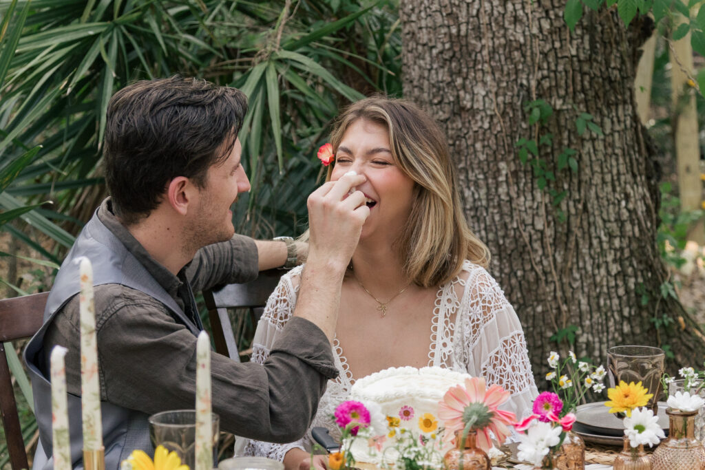 Groom playfully puts frosting on his wife's nose