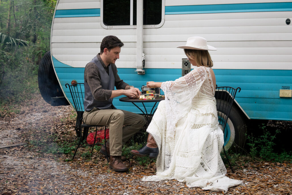 Bride and groom play jenga at their campervan airbnb elopement