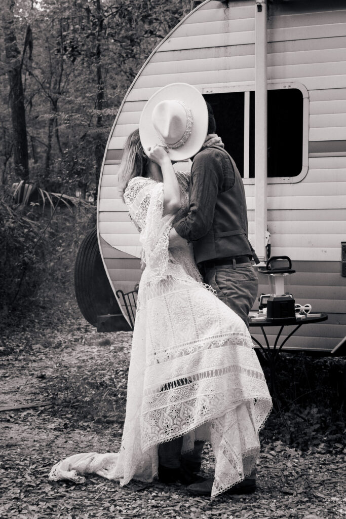 Bride holds up cowgirl hat to hide a kiss with her husband