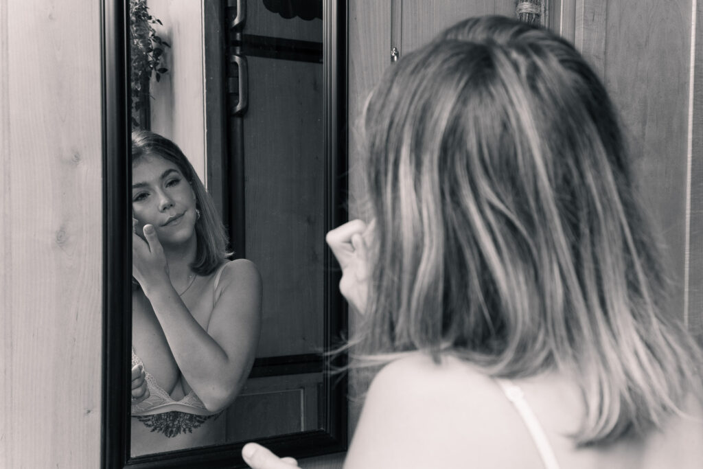 Bride fixes her makeup in the mirror of her campervan airbnb