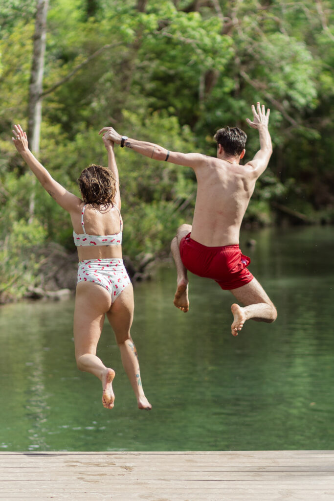 Couple holds hands and jumps off the weeki wachee dock