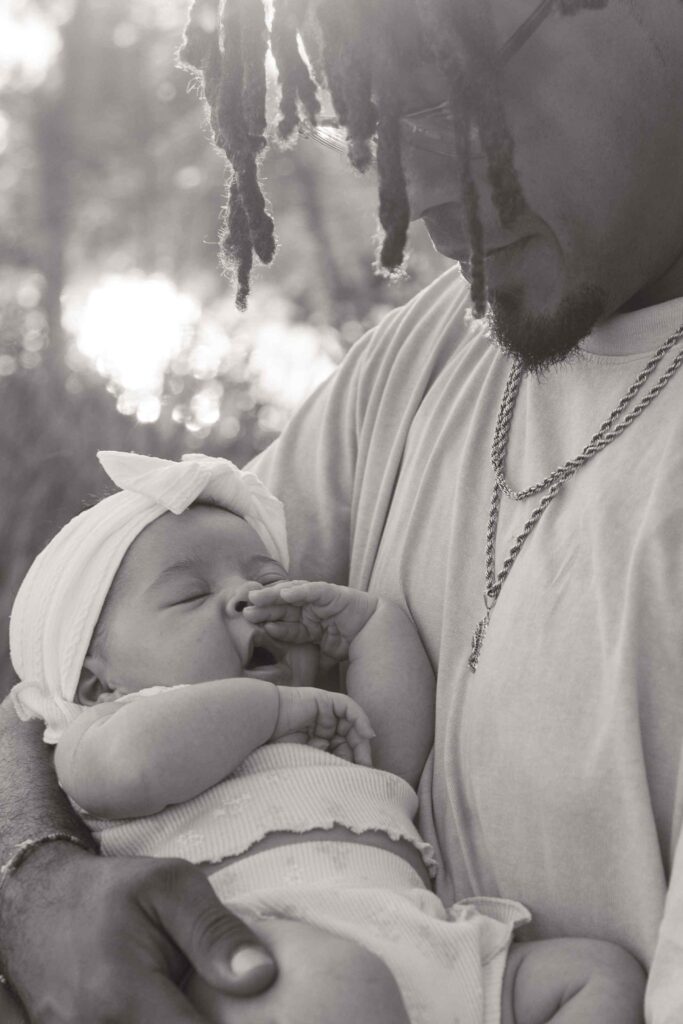 Greyscale photo of a dad holding his infant daughter and smiling down at her