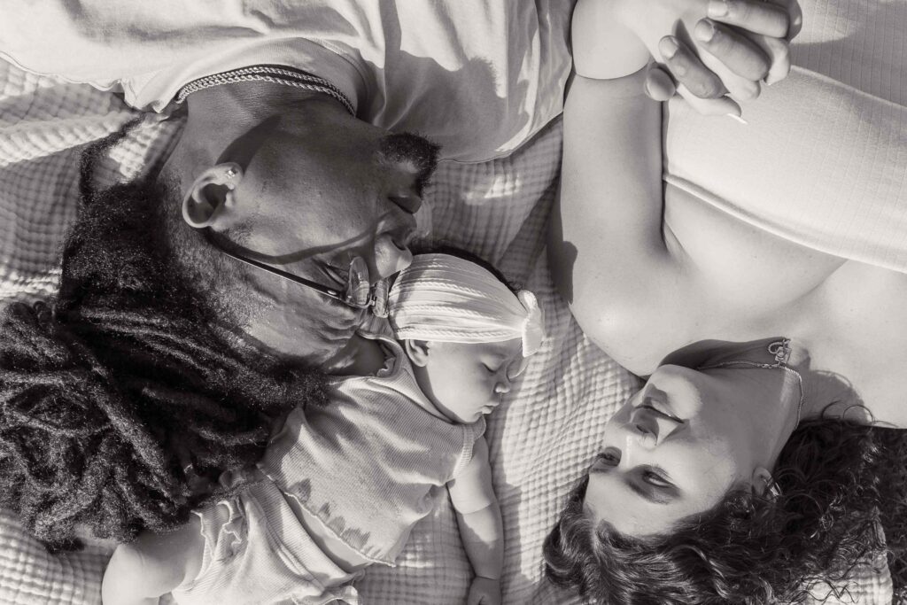 Greyscale of family of three laying on picnic blanket