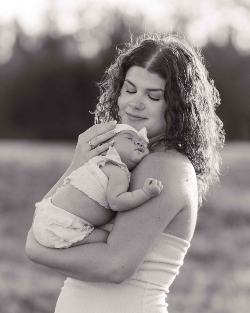 Greyscale of mom hugging infant daughter and smiling down at her