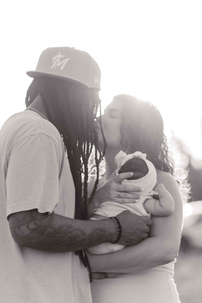 Greyscale parents kiss over infant daughter