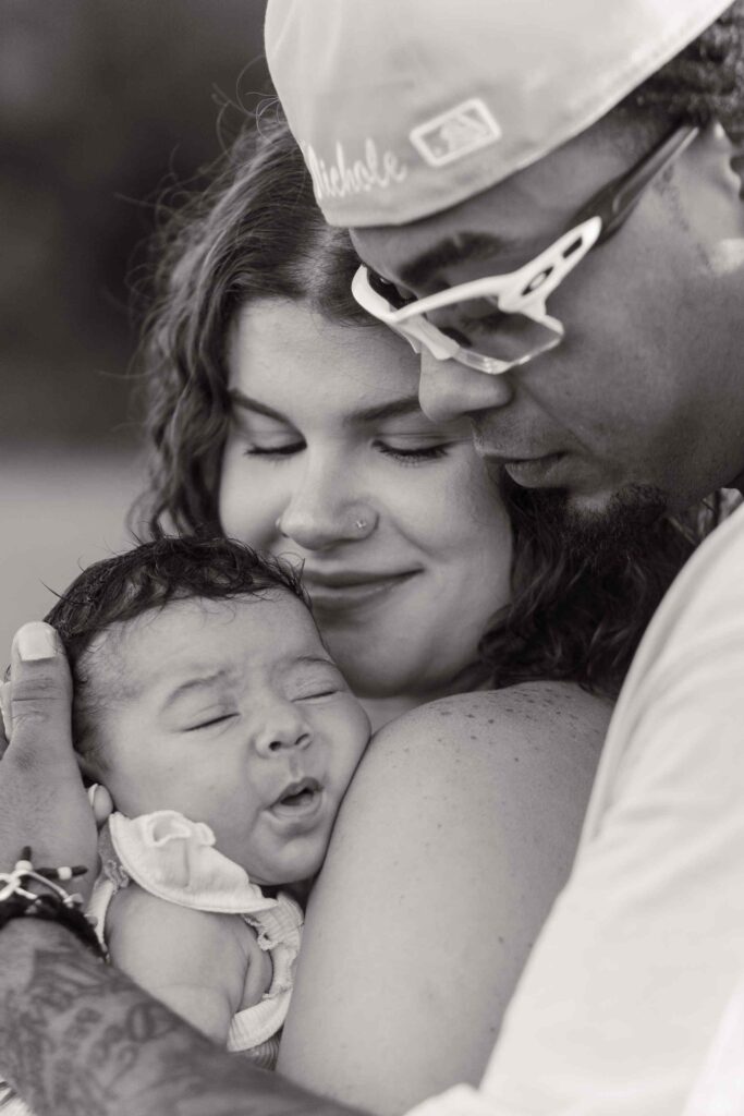 Greyscale closeup of mom, dad, and infant daughter's faces