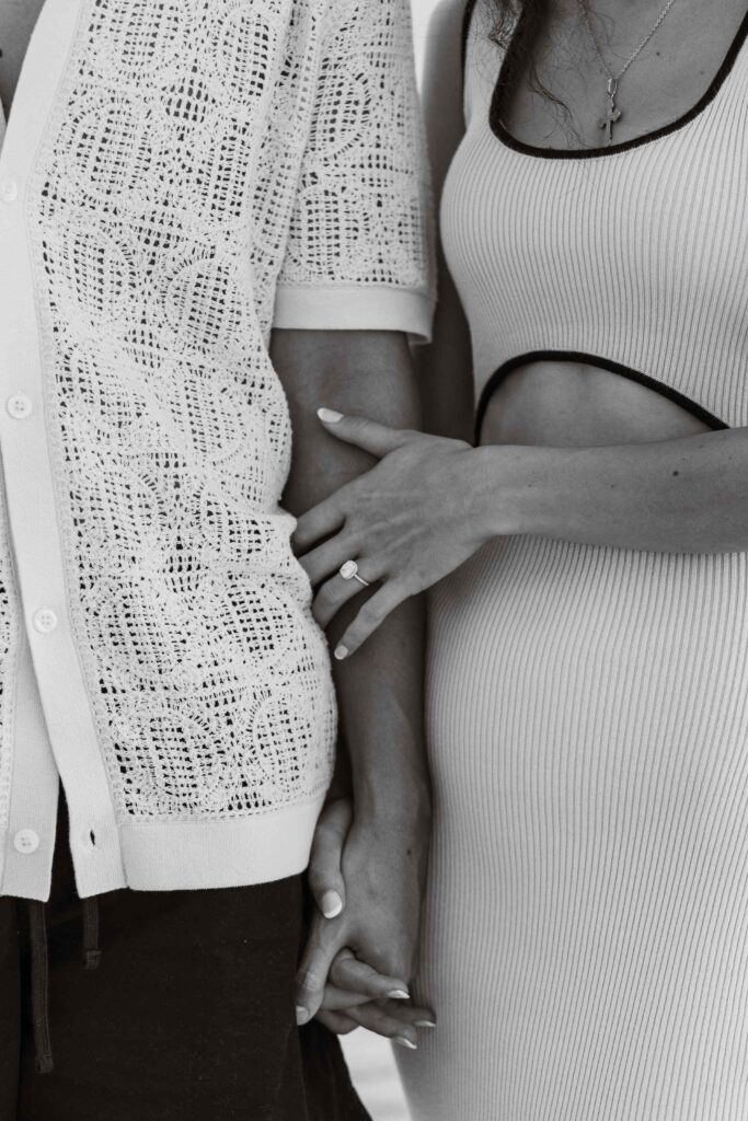 Black and white close up of couple holding hands and Fiancee's new ring