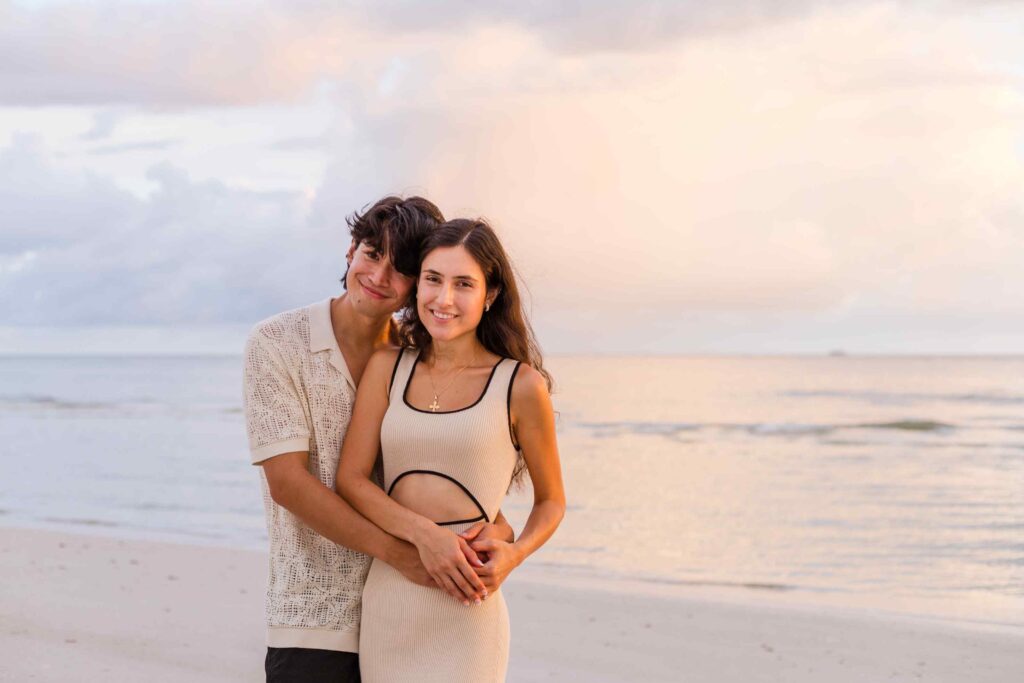 Couple poses in front of a cotton candy colored sky