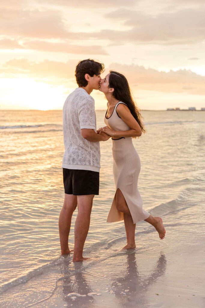 Couple kisses in front of an orange sunset
