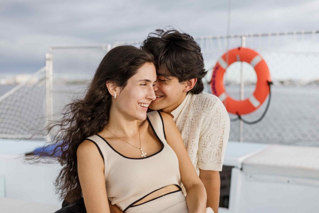 Man whispers into fiance's ear on a boat