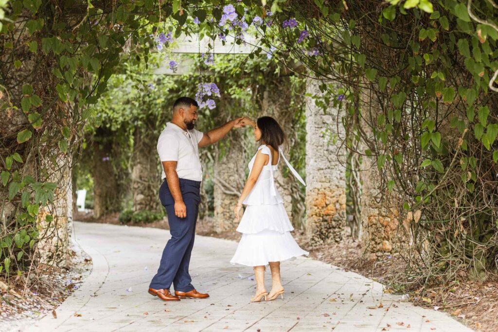 Man twirls fiancée in a flower tunnel