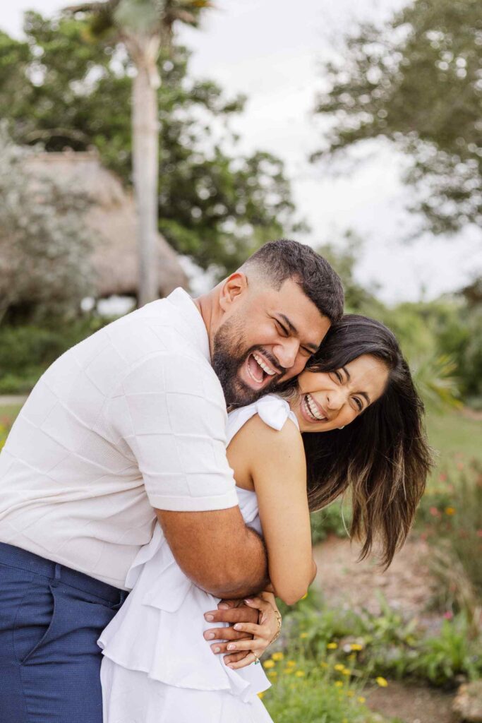 Man hugs fiancée from behind as they're both laughing