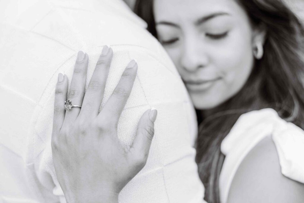 Black and white close up photo of ring with woman's face behind