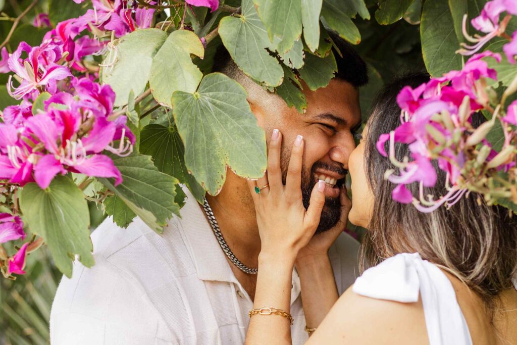 Couple kisses in the middle of a pink flowering tree