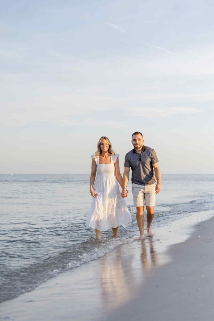 Couple walking towards camera in the shoreline holding hands