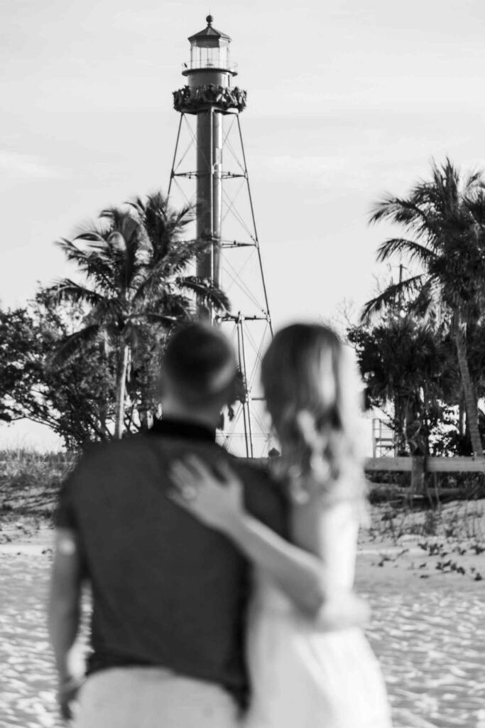 Black and white image of couple's backs as they look towards the Sanibel Lighthouse