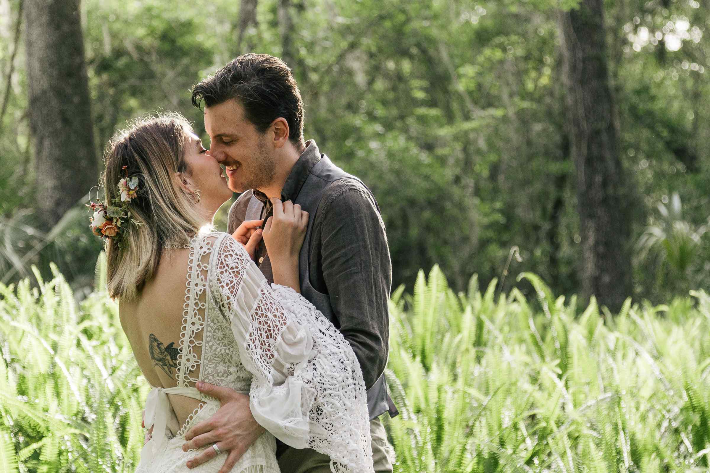 Eloping couple kisses in a field of ferns