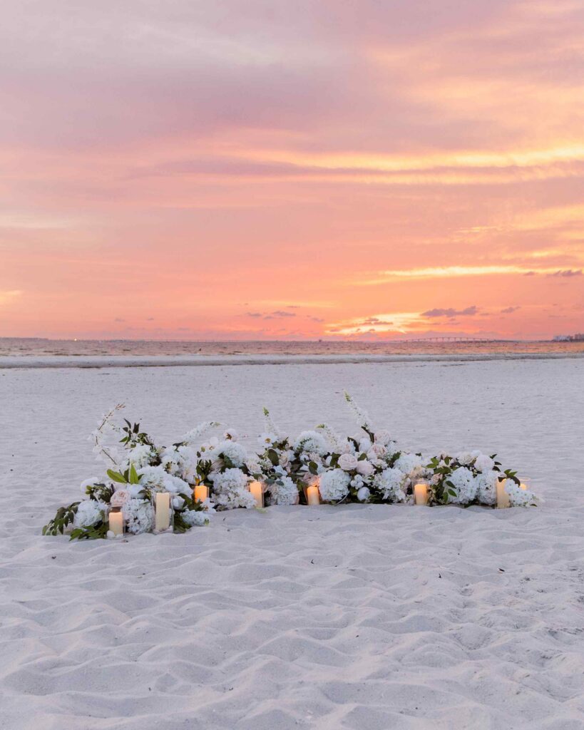 Arch of flowers on the beach at sunset for a marriage proposal
