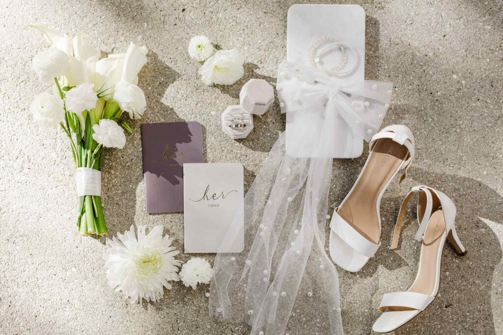Flat lay of elopement details, bouquet, jewelry, vow books